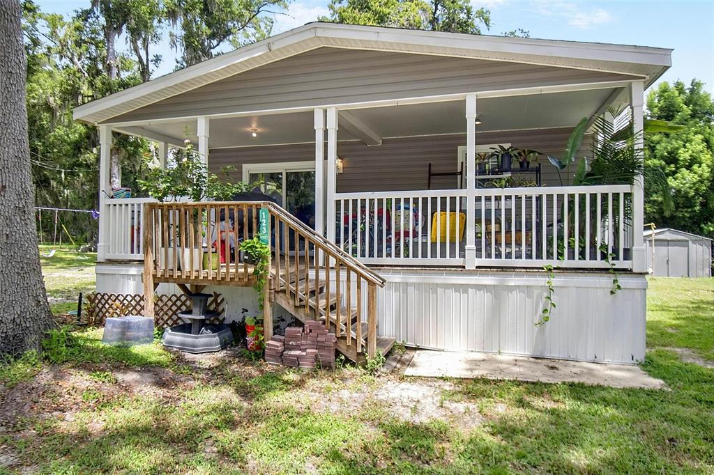An open-concept kitchen and living area features wood-look flooring, a blue island, and brown sofa — 123 MAGNOLIA DRIVE, SATSUMA, FL