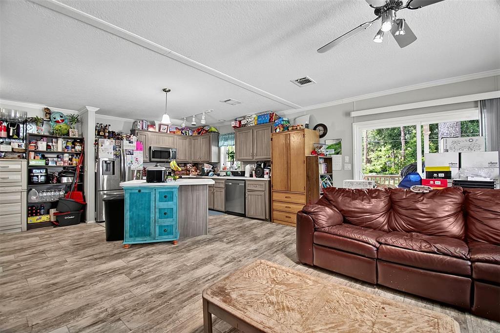 A kitchen features wood cabinets, stainless steel appliances, a central island, and wood-look flooring — 123 MAGNOLIA DRIVE, SATSUMA, FL