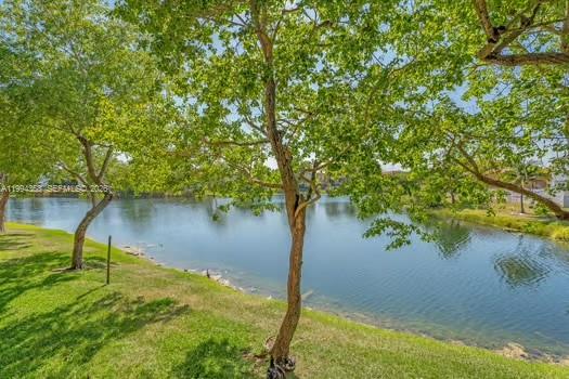 A grassy lawn with trees overlooks a calm lake under a clear blue sky — 15430 SW 82nd Ln # 625, Miami FL 33193, MIAMI, FL