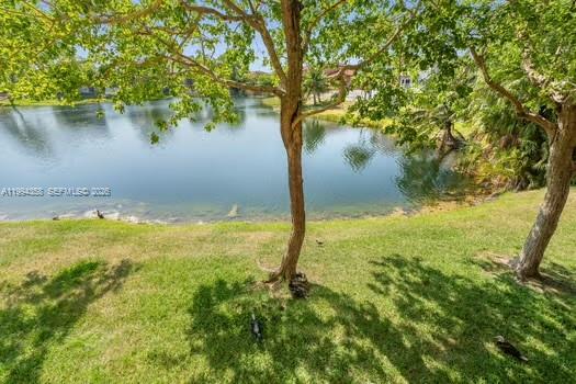 A grassy backyard slopes down toward a calm lake under a bright blue sky — 15430 SW 82nd Ln # 625, Miami FL 33193, MIAMI, FL