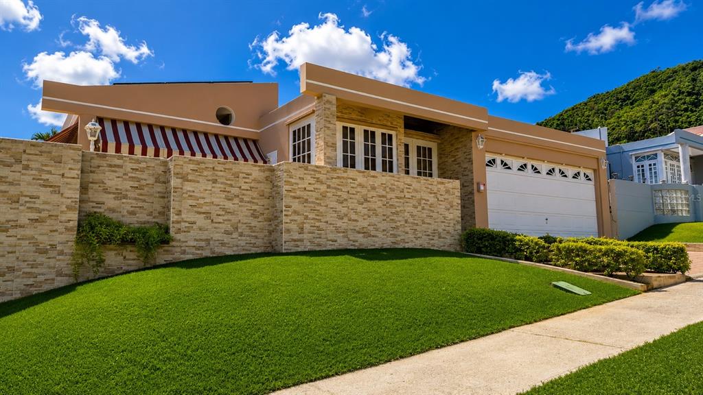 A single-story house with a stone facade, striped awning, and a two-car garage — Calle G #P15 GOLDEN GATE II, CAGUAS, PR