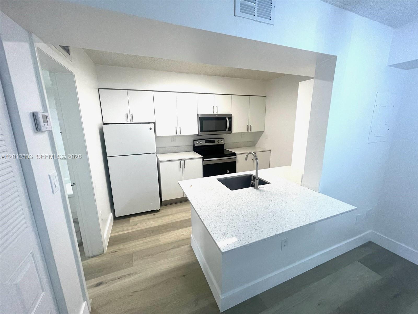 A kitchen features white cabinets, stainless steel appliances, and a central island with a sink — 15201 SW 80th St # 205, Miami FL 33193, MIAMI, FL