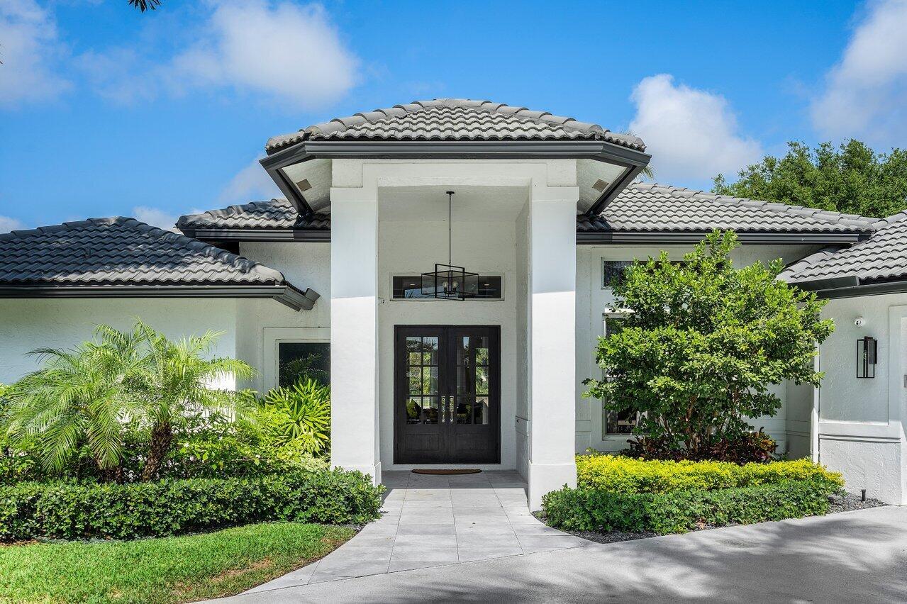 The exterior of a white house features a dark tiled roof and a double-door entrance — 8331 Sawpine Road, Delray Beach FL 33446, DELRAY BEACH, FL
