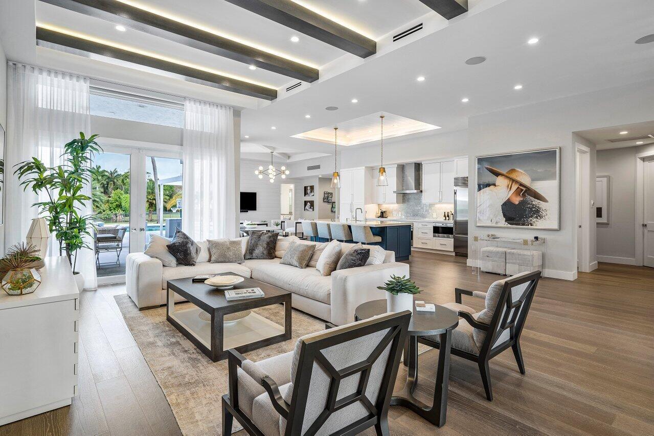 An open-concept living room and kitchen featuring wood floors, coffered ceilings, and a large sectional — 8331 Sawpine Road, Delray Beach FL 33446, DELRAY BEACH, FL