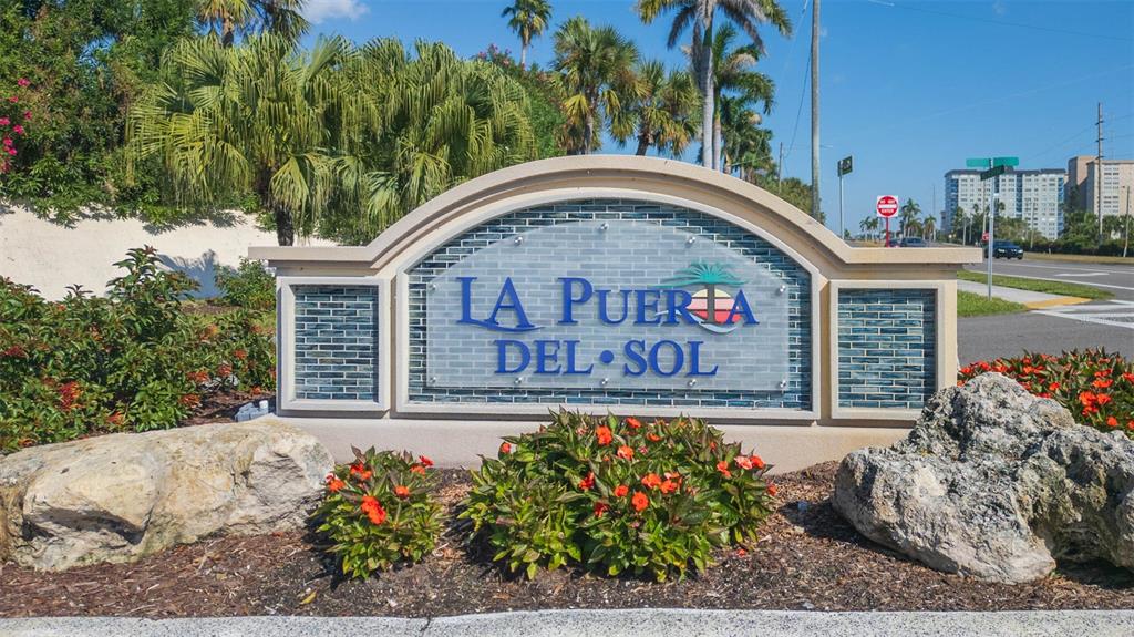 A stone monument sign for La Puerta del Sol stands in a landscaped garden area — 5633 PUERTA DEL SOL BOULEVARD S UNIT 208, ST PETERSBURG, FL