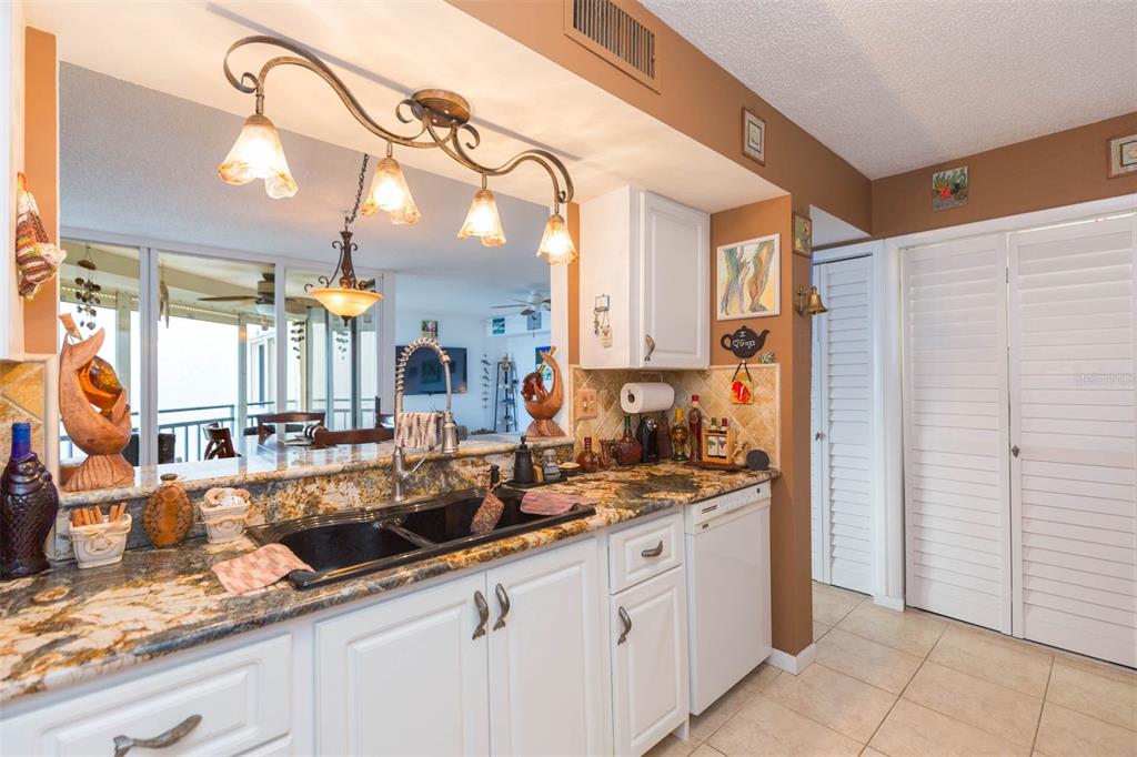A kitchen features white cabinets, granite countertops, a double sink, and a hanging light fixture — 5633 PUERTA DEL SOL BOULEVARD S UNIT 208, ST PETERSBURG, FL