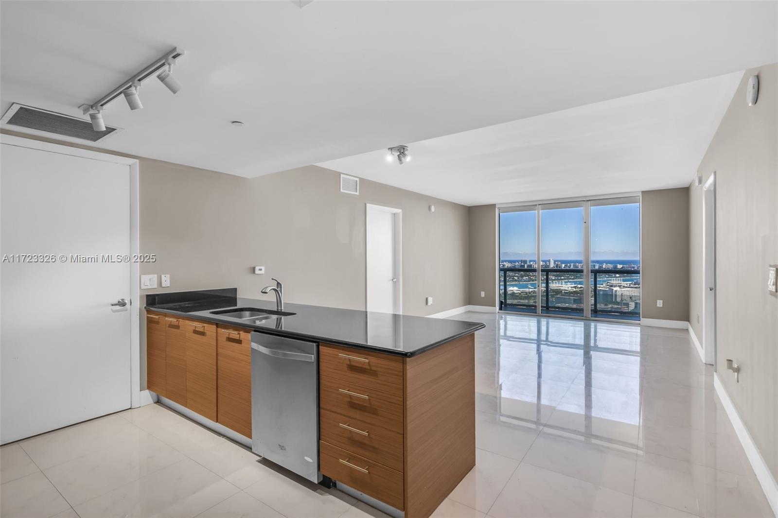 A kitchen island with a stainless steel dishwasher faces a living area with floor-to-ceiling windows — 50 Biscayne Blvd # 4208, Miami FL 33132, MIAMI, FL