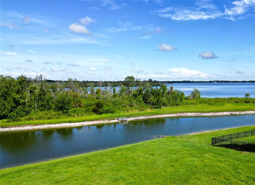 An elevated view of a grassy yard, a narrow pond, and a large lake beyond — 493 ADAMS VIEW LANE, AUBURNDALE, FL