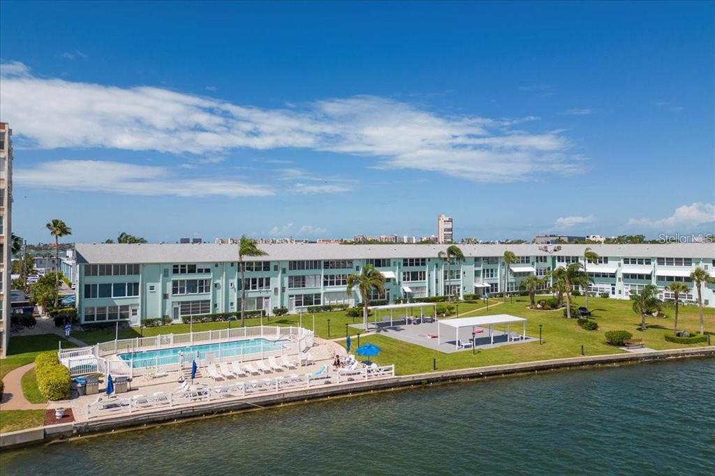 An aerial view of a waterfront apartment complex with a swimming pool and lawn area — 1819 SHORE DRIVE S UNIT 110, SOUTH PASADENA, FL