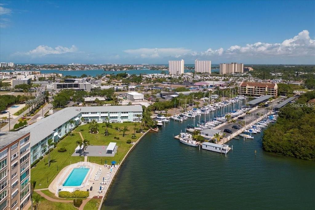 An aerial view shows a waterfront apartment complex with a pool and a boat marina — 1819 SHORE DRIVE S UNIT 110, SOUTH PASADENA, FL