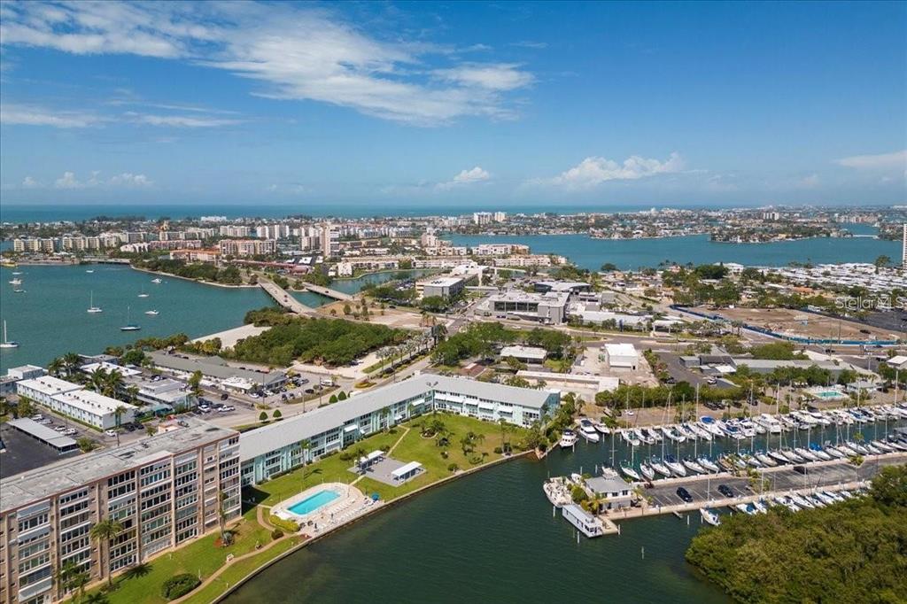 An aerial view shows a waterfront apartment complex with a pool and a boat marina — 1819 SHORE DRIVE S UNIT 110, SOUTH PASADENA, FL