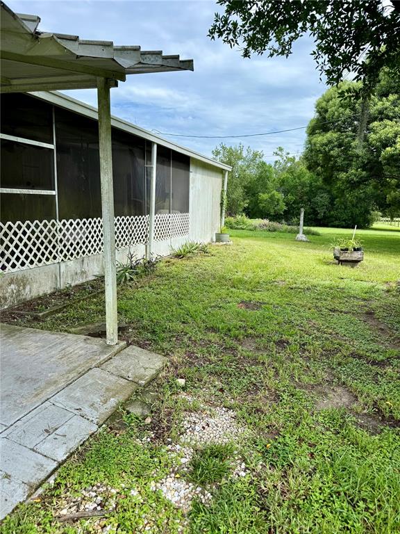A side view of a house with a screened-in porch and a concrete patio — 39605 OTIS ALLEN ROAD, ZEPHYRHILLS, FL