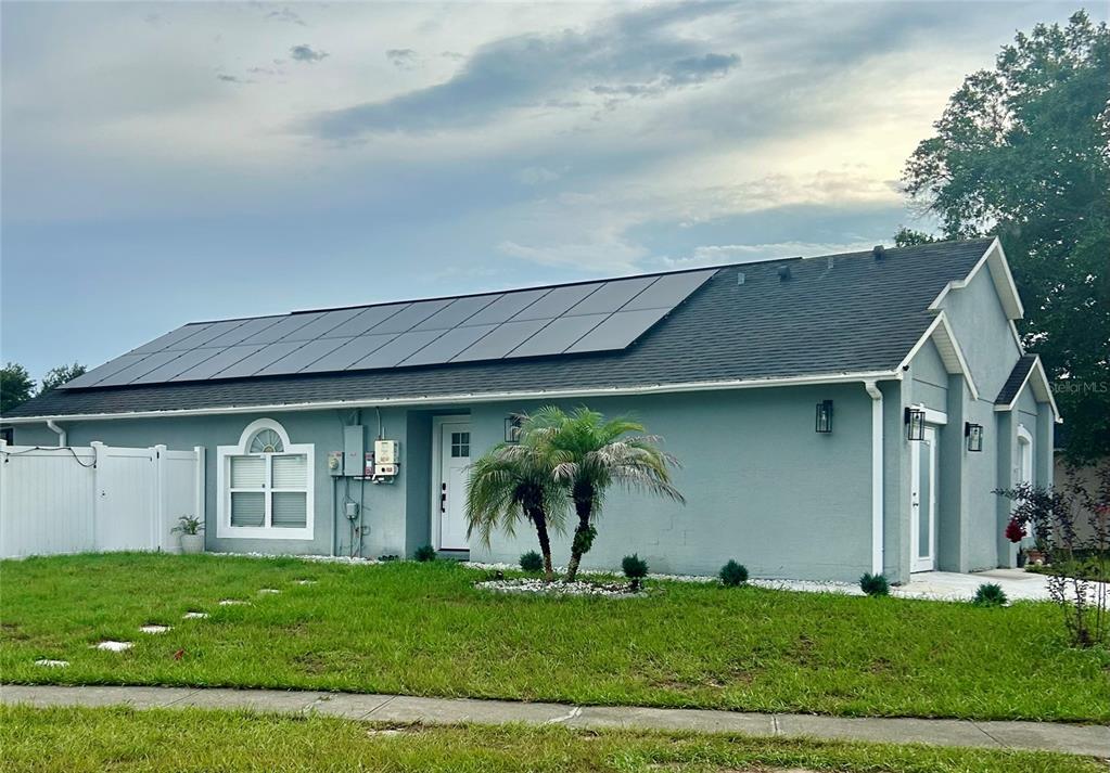 A single-story house with a gray exterior, solar panels on the roof, and a palm tree — 5524 NEW CAMBRIDGE ROAD, ORLANDO, FL