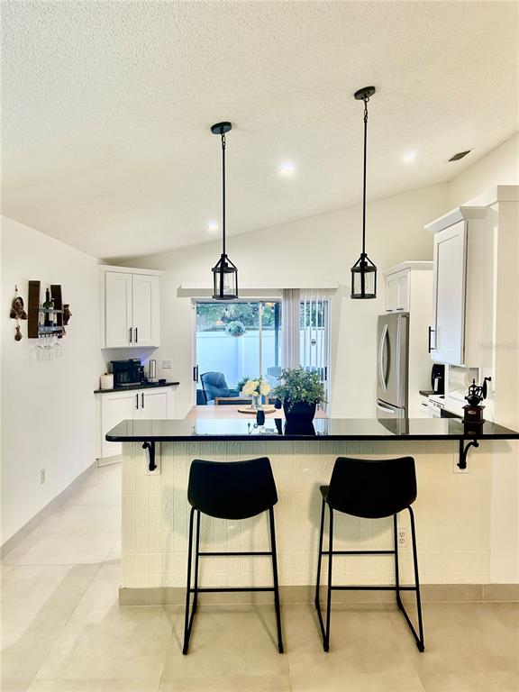A kitchen features white cabinets, a black countertop breakfast bar, and two black pendant lights — 5524 NEW CAMBRIDGE ROAD, ORLANDO, FL