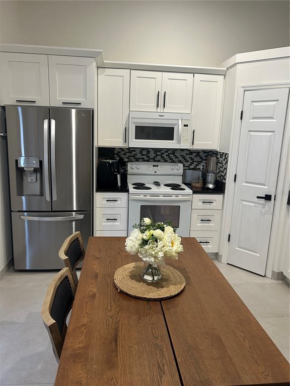 A kitchen features white cabinets, stainless steel appliances, and a wooden dining table with flowers — 5524 NEW CAMBRIDGE ROAD, ORLANDO, FL