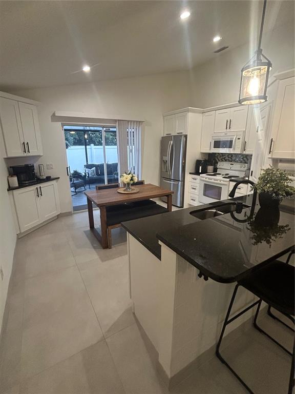 A kitchen features white cabinets, black countertops, a dining area, and a sliding glass door — 5524 NEW CAMBRIDGE ROAD, ORLANDO, FL