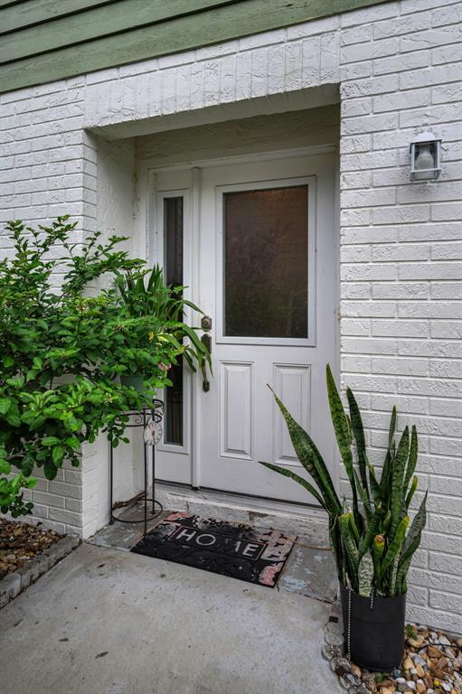 A white front door with a side window is framed by white brick walls — 3215 MCMATH DRIVE, PALM HARBOR, FL