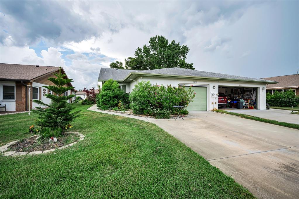 A single-story house with a green garage door, a concrete driveway, and a landscaped lawn — 3215 MCMATH DRIVE, PALM HARBOR, FL