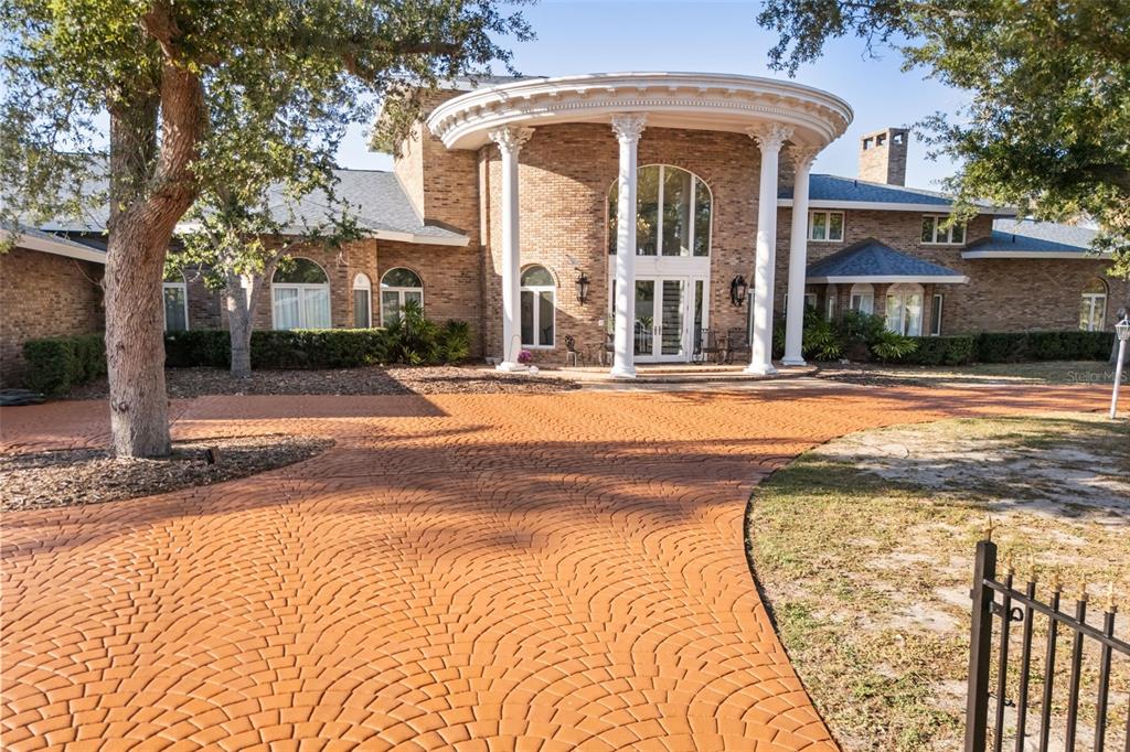 A large brick house features a circular portico with white columns and a patterned driveway — 6118 RIVERVIEW BOULEVARD, BRADENTON, FL