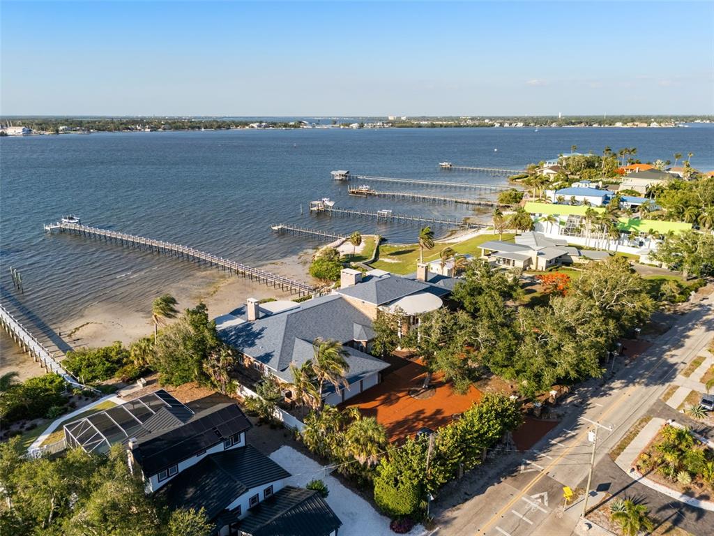 An aerial view shows a waterfront house with a long dock extending into the bay — 6118 RIVERVIEW BOULEVARD, BRADENTON, FL
