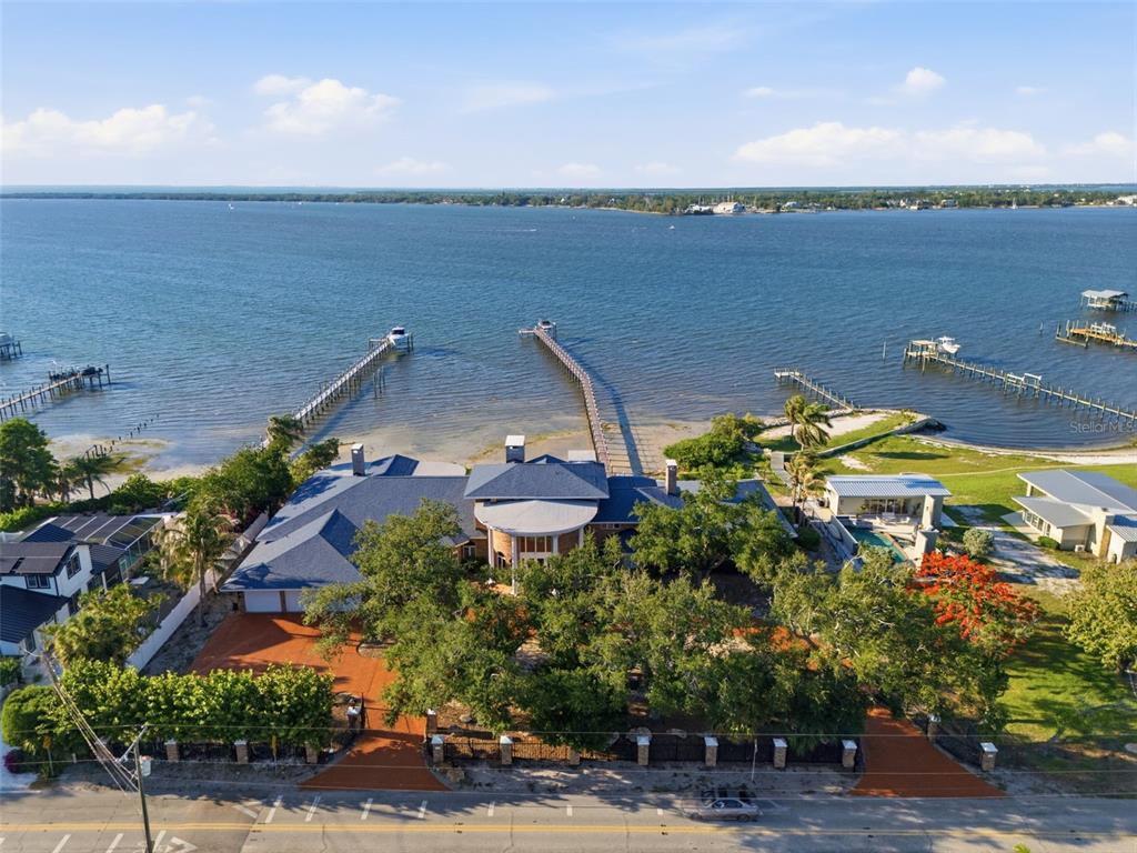 An aerial view shows a waterfront house with two long docks extending into the bay — 6118 RIVERVIEW BOULEVARD, BRADENTON, FL