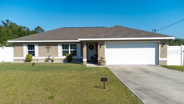 A single-story house with a tan exterior, white trim, and a two-car garage — 227 OAK LANE LOOP, OCALA, FL