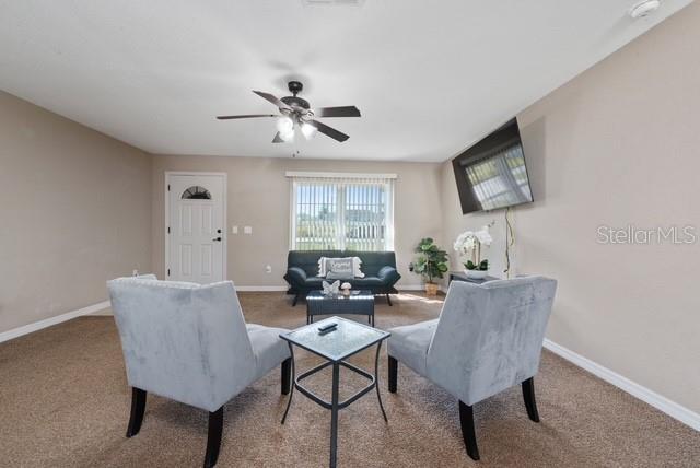 A living room features two gray armchairs, a dark sofa, and a wall-mounted television — 227 OAK LANE LOOP, OCALA, FL