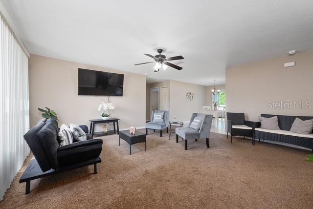 A living room features a dark sofa, armchairs, a television, and beige carpeting — 227 OAK LANE LOOP, OCALA, FL