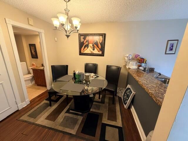 A dining area features a glass table, four black chairs, and a chandelier — 3711 37th Way, West Palm Beach FL 33407, WEST PALM BEACH, FL
