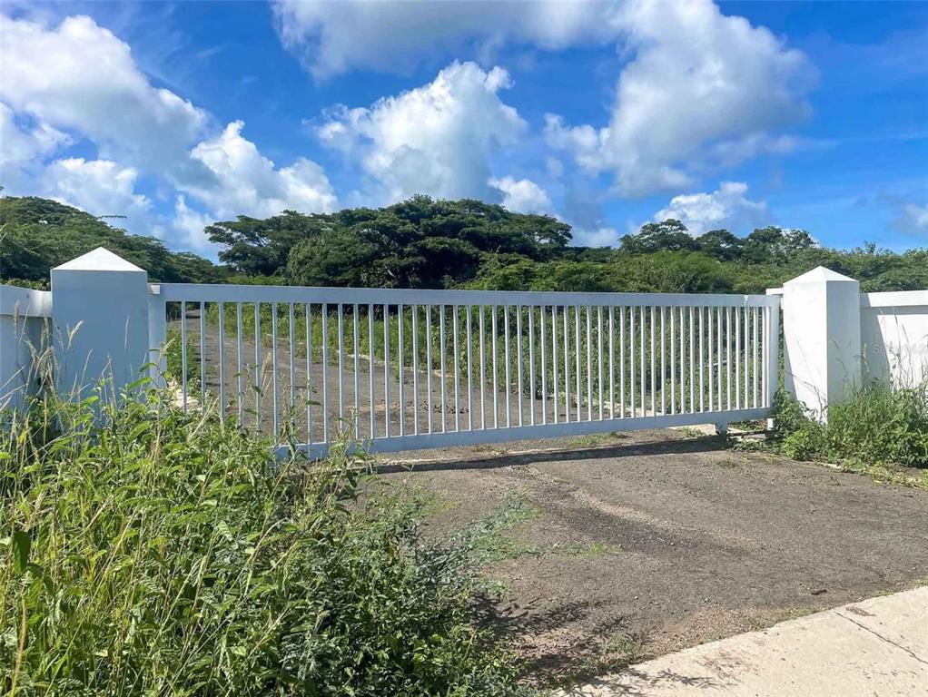 A white metal gate stands between two concrete pillars at the entrance to a lot — 2C HACIENDA PUERTO REAL, VIEQUES, PR