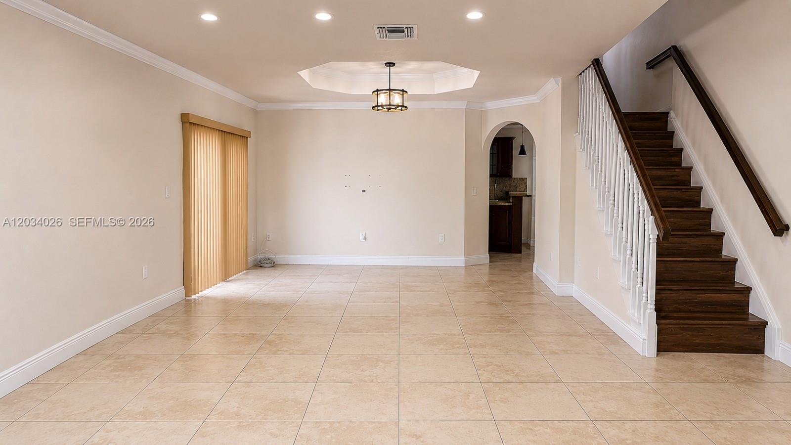 An empty living room features beige tile flooring, a staircase, and a recessed ceiling light — 12211 SW 137th Ter, Miami FL 33186, MIAMI, FL