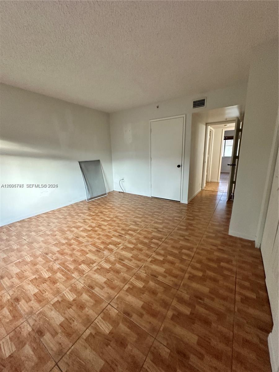 An empty room features light-colored walls, a white door, and patterned brown tile flooring — 551 NW 82nd Ave # 502, Miami FL 33126, MIAMI, FL