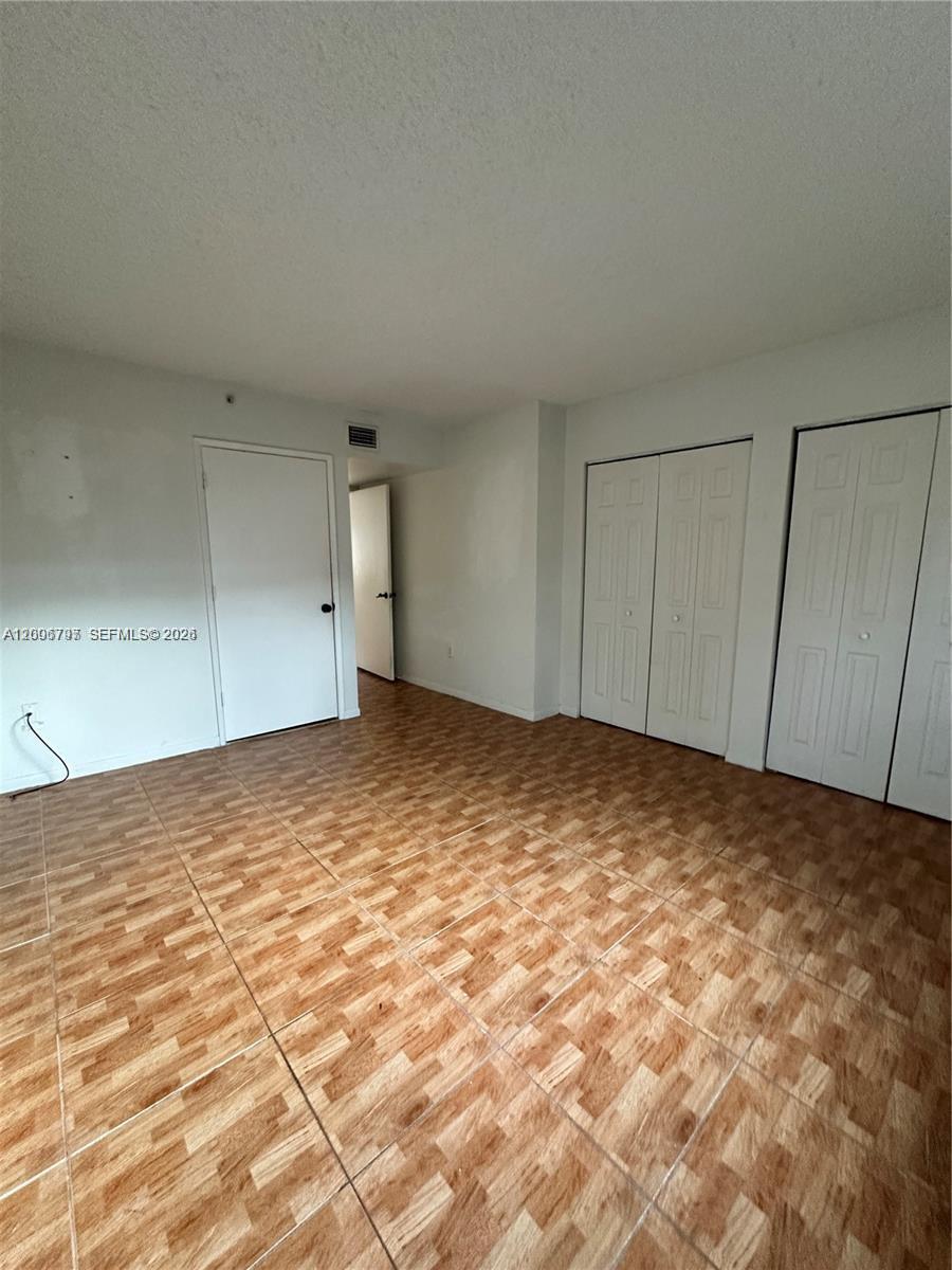 An empty room features white walls, a tiled floor, and several white closet doors — 551 NW 82nd Ave # 502, Miami FL 33126, MIAMI, FL