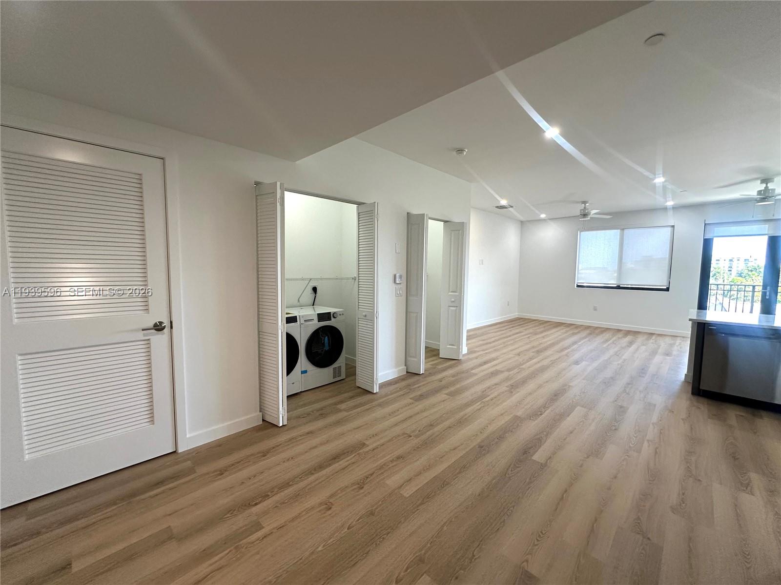 An interior view shows a room with light wood flooring, a laundry closet, and windows — 20 NE 19th Ave, Pompano Beach FL 33060, POMPANO BEACH, FL