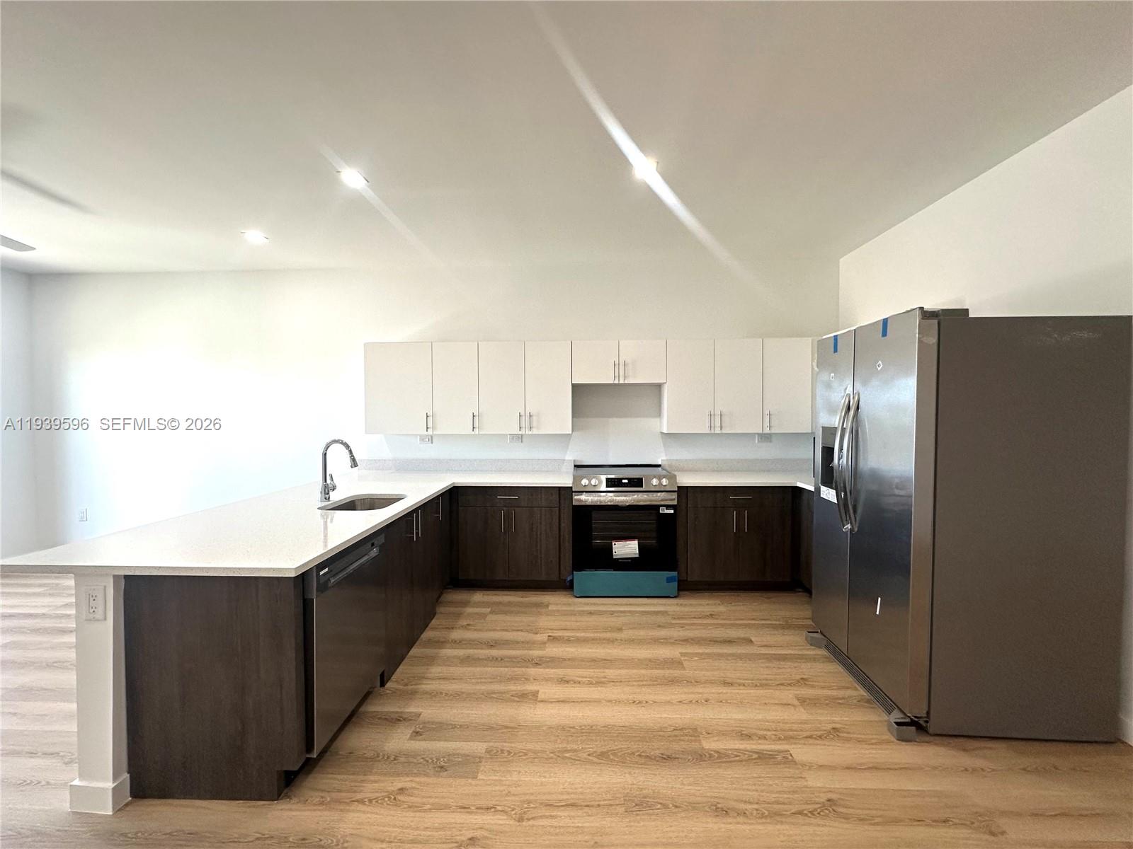 A modern kitchen features white upper cabinets, dark lower cabinets, stainless steel appliances, and quartz countertops — 20 NE 19th Ave, Pompano Beach FL 33060, POMPANO BEACH, FL