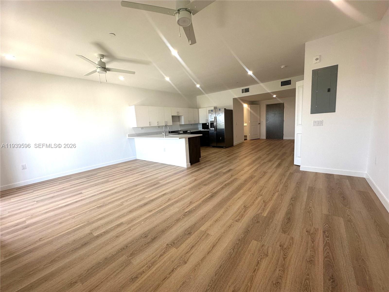 An open-concept living area features light wood-look flooring, white cabinetry, and two ceiling fans — 20 NE 19th Ave, Pompano Beach FL 33060, POMPANO BEACH, FL