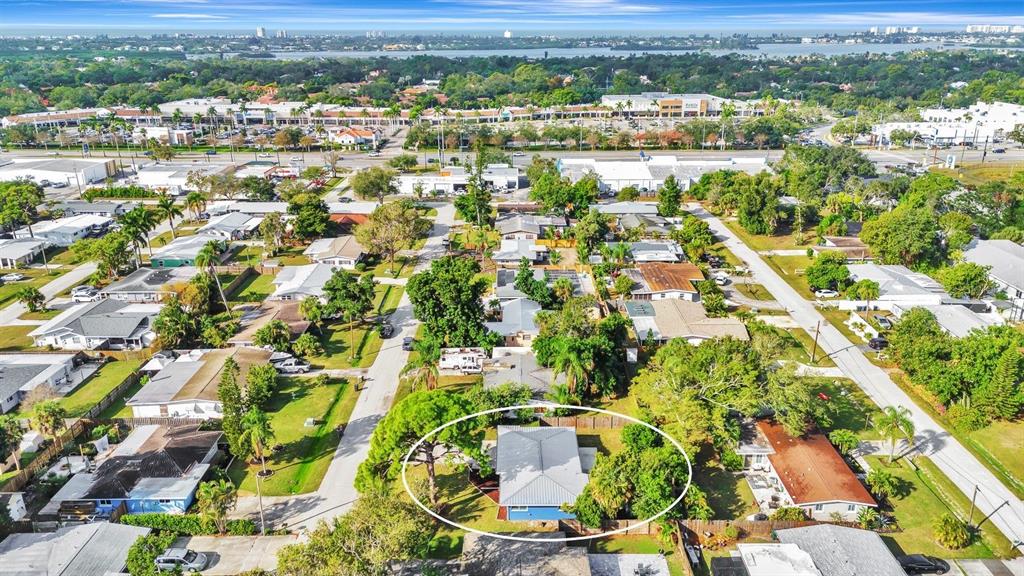 An aerial view shows a blue house with a metal roof surrounded by lush trees — 2127 LEE LANE, SARASOTA, FL