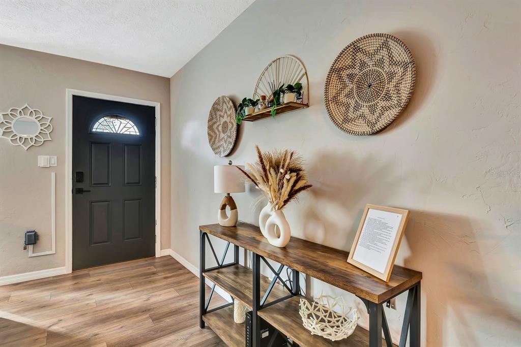 An entryway features a dark door, wood-look flooring, and a console table with decor — 2127 LEE LANE, SARASOTA, FL