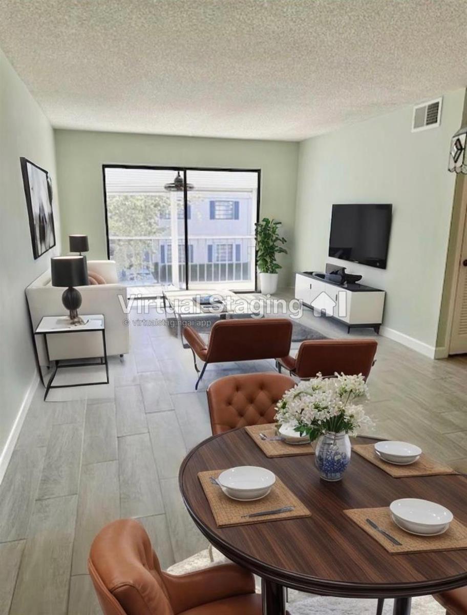 This living and dining area features light green walls, wood-look tile flooring, and virtual staging — 130 Cypress Club Drive Apt 323, Pompano Beach FL 33060, POMPANO BEACH, FL