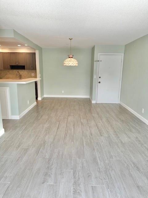 An open-concept living area features light green walls, wood-look tile flooring, and a pendant light — 130 Cypress Club Drive Apt 323, Pompano Beach FL 33060, POMPANO BEACH, FL