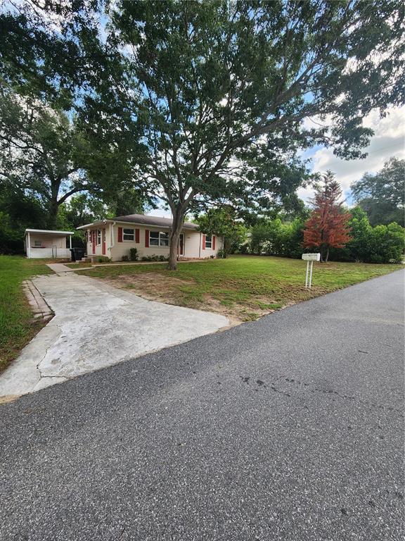 A single-story house with a concrete driveway, a detached carport, and a large front yard — 4320 HEDGE DRIVE N, LAKELAND, FL