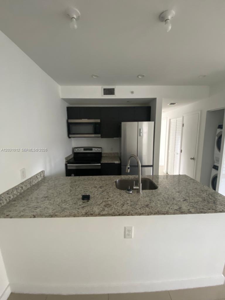 A kitchen features granite countertops, dark cabinetry, stainless steel appliances, and a breakfast bar — 423 E 27th St # 302, Hialeah FL 33013, HIALEAH, FL