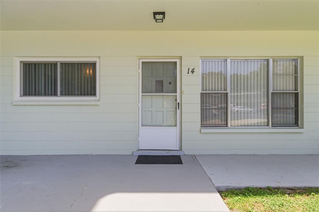 The exterior of a light green building features a front door numbered 14 and windows — 2386 SUMATRAN WAY UNIT 14, CLEARWATER, FL