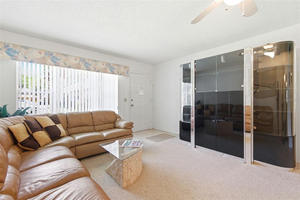 A living room features a tan leather sectional, a glass coffee table, and black cabinetry — 2386 SUMATRAN WAY UNIT 14, CLEARWATER, FL