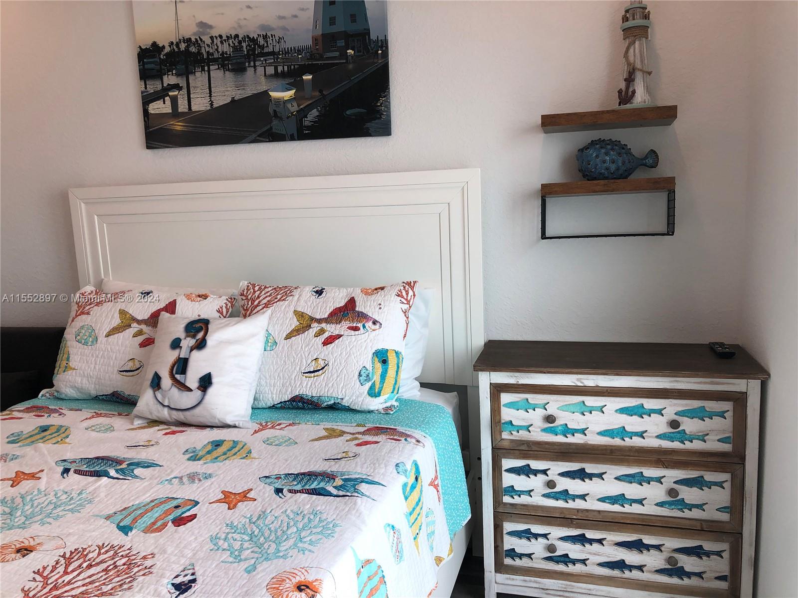 A bedroom features a nautical-themed quilt, a fish-patterned dresser, and a lighthouse wall decor — 10877 Overseas Hwy # 38, Marathon FL 33050, MARATHON, FL