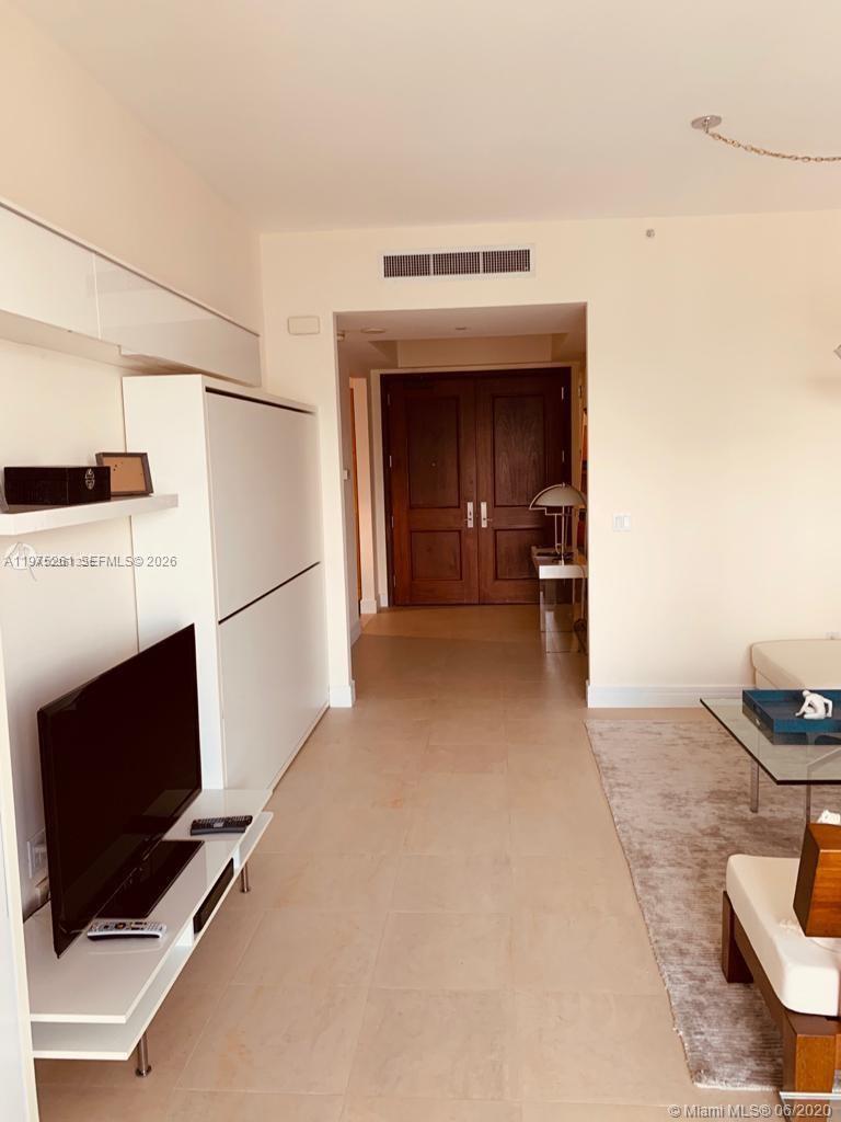 A living room features a white wall unit, a television, and a doorway with double doors — 1425 Brickell Ave # 43D, Miami FL 33131, MIAMI, FL