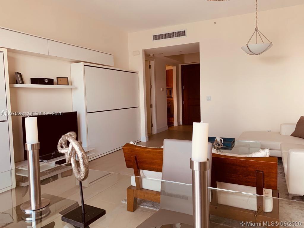A living room features a white wall unit, a dining table, and a white sofa — 1425 Brickell Ave # 43D, Miami FL 33131, MIAMI, FL