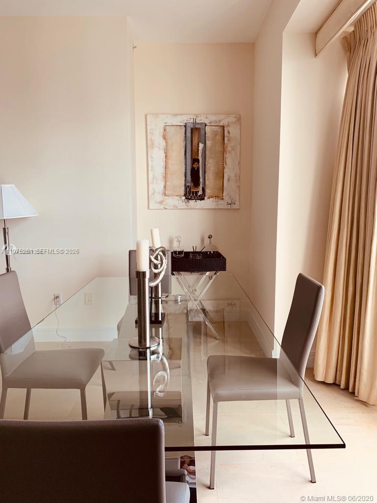 A dining room features a glass table, four gray chairs, and a piece of wall art — 1425 Brickell Ave # 43D, Miami FL 33131, MIAMI, FL