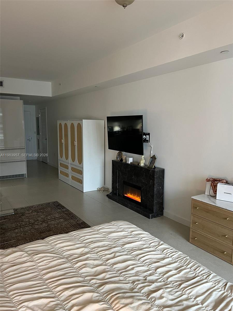 A bedroom features a bed, a wall-mounted television above a fireplace, and a storage cabinet — 1010 Brickell Ave # 2010, Miami FL 33131, MIAMI, FL