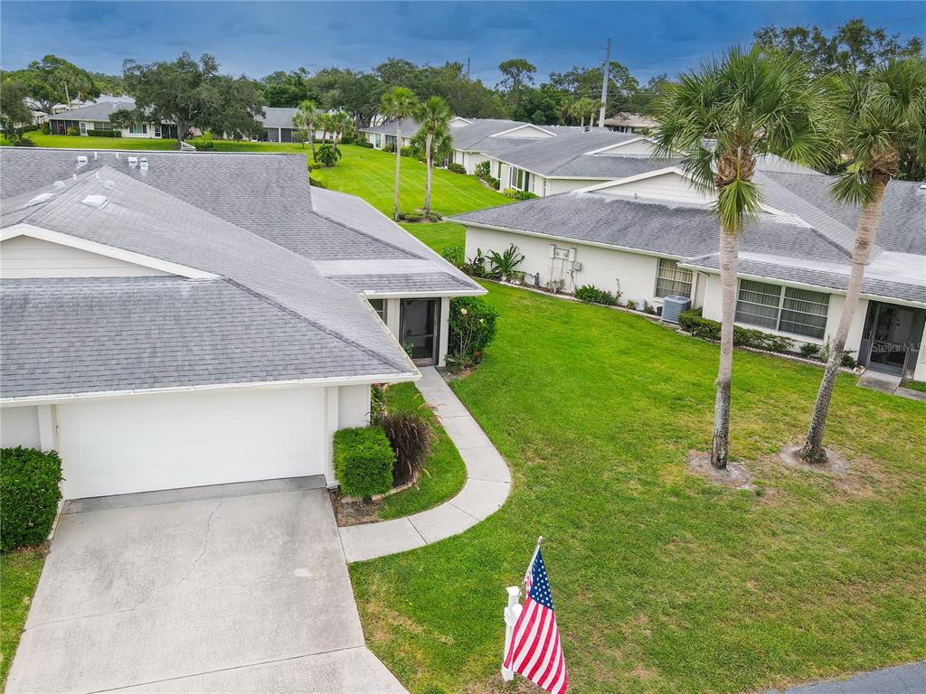 An aerial view shows two single-story residential buildings with gray roofs and a shared lawn — 4136 BOWLING GREEN CIRCLE UNIT 23, SARASOTA, FL